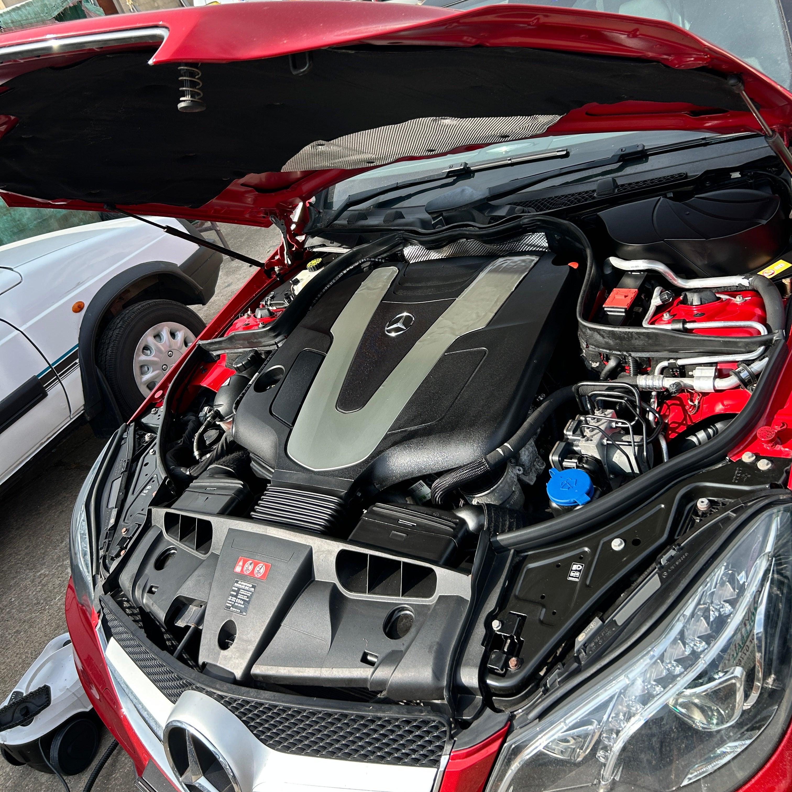 Close-up of a car engine bay with visible branding in an urban setting.