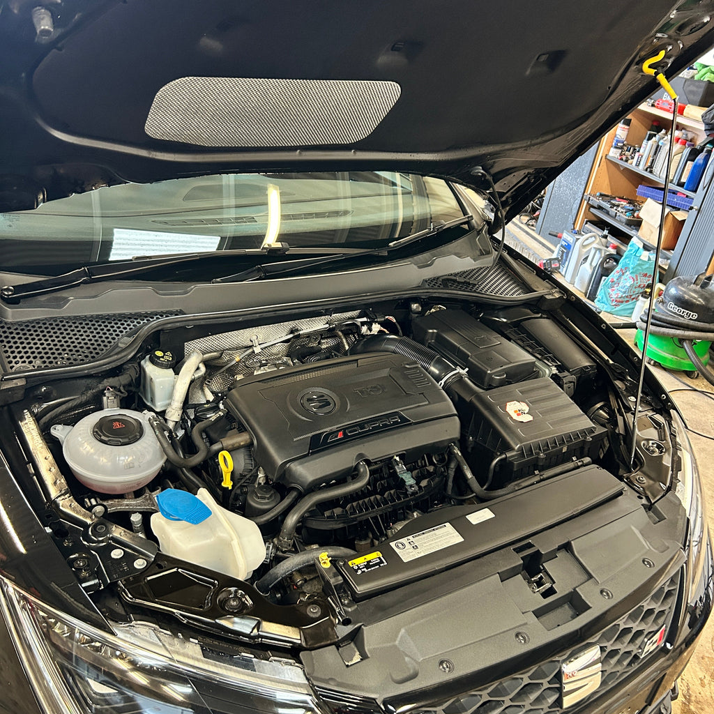 Car engine compartment with open hood in a workshop setting